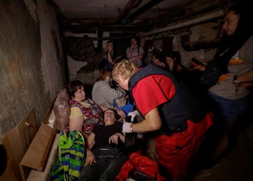 A medical worker treats a woman as residents take refuge in the basement of their apartment building during a Russian attack, in Kharkiv, Ukraine, July 7, 2025.