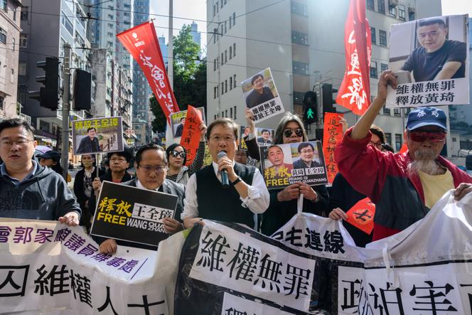 Ativistas Brandish Retratos do advogado Wang Quanzhang e o fundador do site 64 Tianwang, dedicado aos direitos humanos, Huang Qi, durante uma demonstração em Hong Kong em 29 de janeiro de 2019.