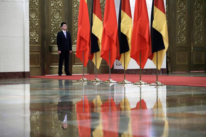 Un membre du personnel de sécurité monte la garde à côté des drapeaux chinois et allemand, à Pékin, le 24 mai 2018.