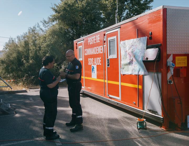 Le colonel Christophe Magny et une co-équipière devant le poste de commandement des sapeurs-pompiers de Narbonne, dans les environs de Bages (Aude), le 9 juillet 2025.