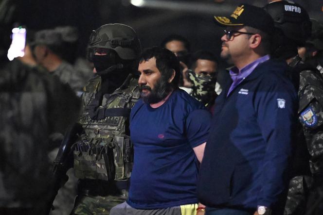 Le trafiquant de drogue Adolfo Macias, alias « Fito », est gardé par le ministre de l’intérieur équatorien John Reimberg (à droite) et du personnel militaire, à son arrivée à la base aérienne de Guayaquil, en Equateur, le 25 juin 2025.