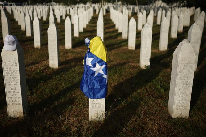 Un drapeau bosniaque sur une pierre tombale au centre de commémoration des personnes tuées lors du génocide de Srebrenica à Potocari, en Bosnie, le 11 juillet 2025.