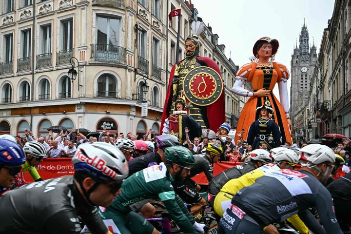 Le peloton passe devant des géants, des personnages de la tradition nordiste, lors de la deuxième étape du Tour de France entre Lauwin-Planque (Nord) et Boulogne-sur-Mer (Pas-de-Calais), le 6 juillet 2025.