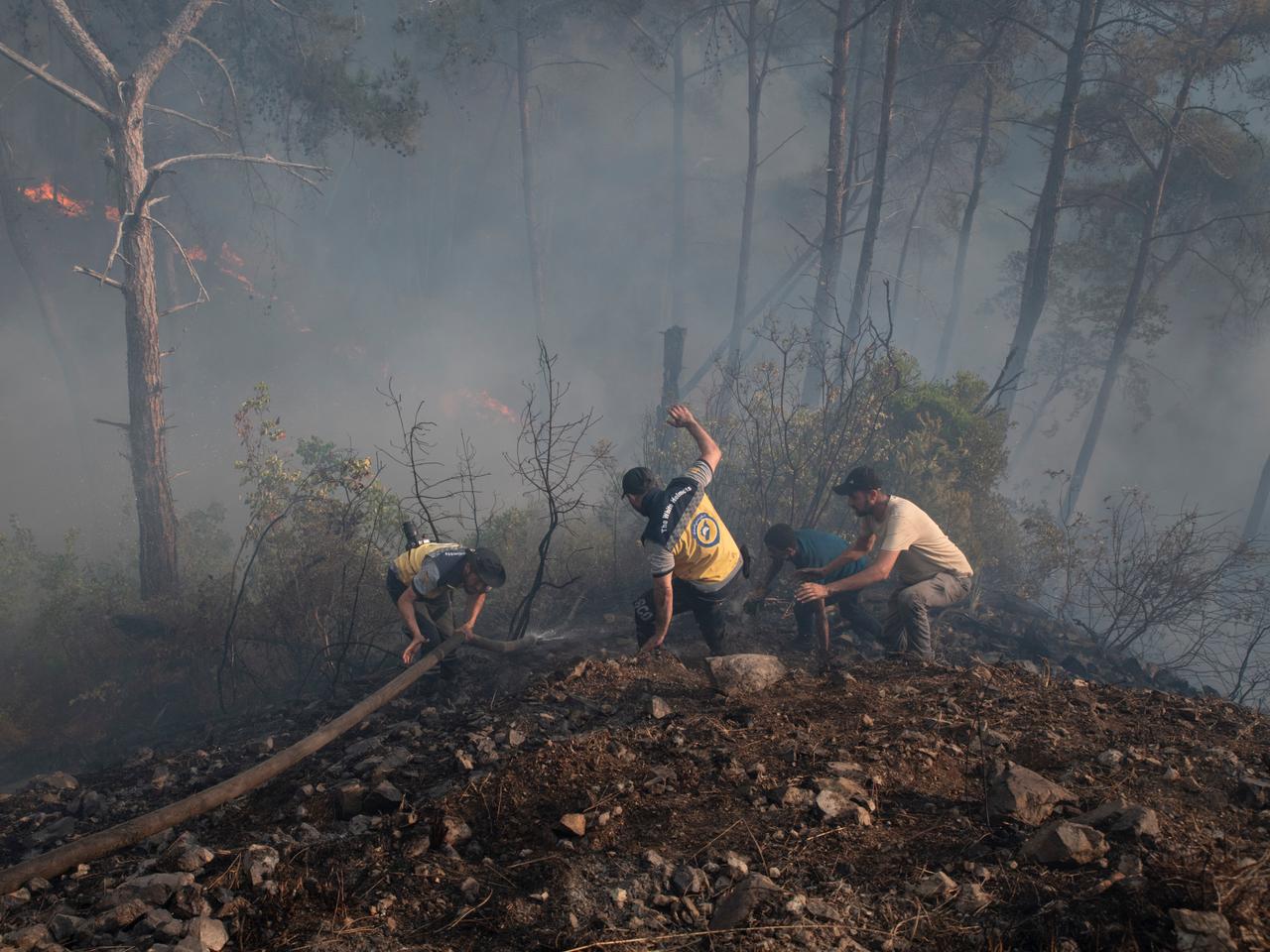 Overwhelmed by the advancing flames, members of the White Helmets, supported by Syrian volunteers, tried to retrieve a fire hose before fleeing one of the blazes ravaging the Eagle Mountain range (Jabal al-Nisr, in Arabic). Latakia, Syria, July 9, 2025.