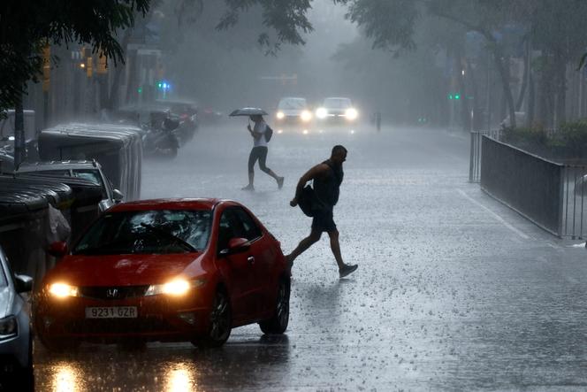 As pessoas atravessam uma rua durante uma chuva em Barcelona, Catalunha, no leste da Espanha, em 12 de julho de 2025.