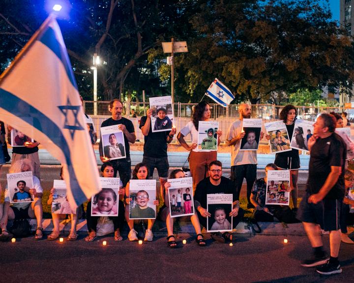 Des manifestants se tiennent sur le bord de la route rue Kaplan, tenant des photos d’enfants Gazaouis morts lors d’une manifestation pour un cessez-le-feu à Tel Aviv, le 12 juillet 2025.