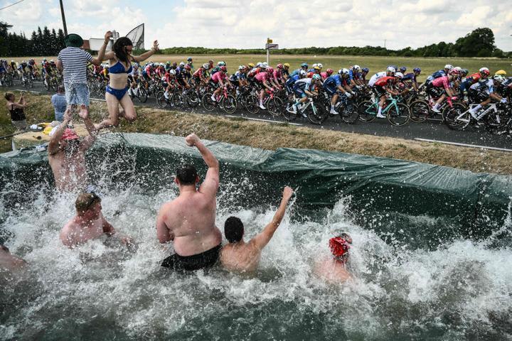 Des spectateurs dans une piscine improvisée saluent le passage du peloton lors de la neuvième étape entre Chinon (Indre-et-Loire) et Châteauroux, le 13 juillet 2025.