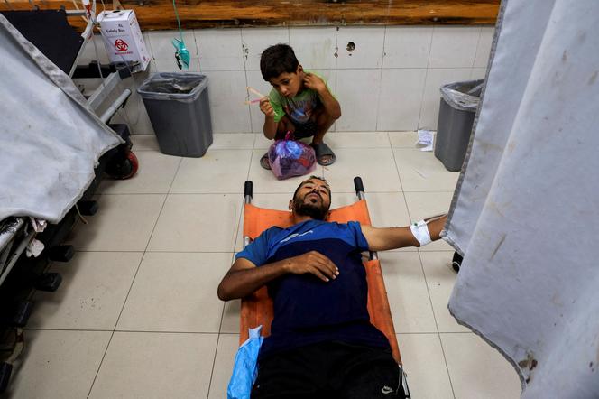 Um palestino ferido em ataques israelenses em Khan Younès e seu filho, no Hospital Nasser. Em Khan Younès, 14 de julho de 2025.