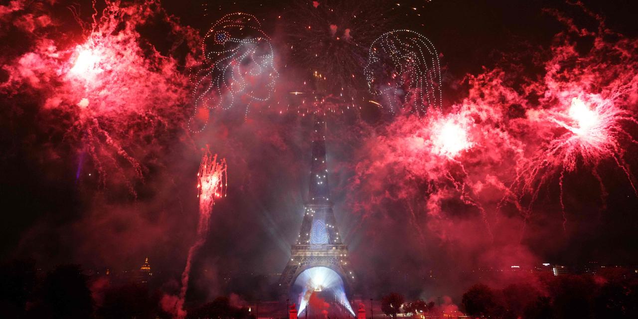 DIMITAR DILKOFF / AFP TOPSHOT - Fireworks explode around the Eiffel Tower as drones form two faces in profile during a choreographed light show to celebrate Bastille Day, in Paris, on July 14, 2025. (Photo by Dimitar DILKOFF / AFP)