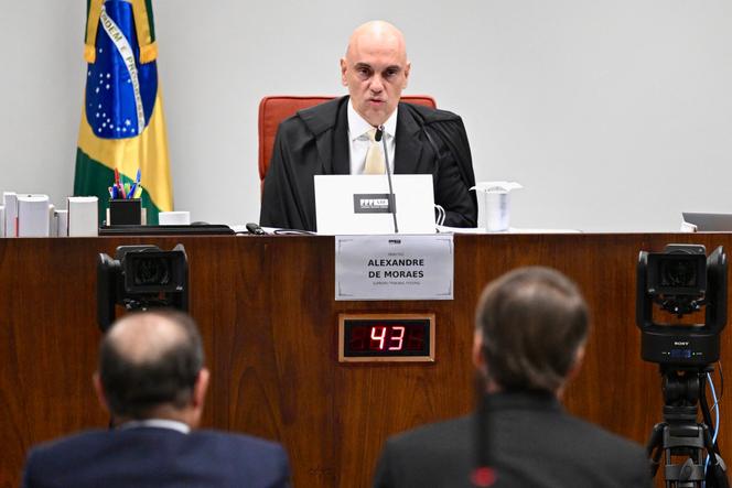 L’ancien président brésilien Jair Bolsonaro (de dos à droite), assis à côté de son avocat Celso Villardi (à gauche),  devant le juge Alexandre de Moraes lors d’une session de procès de la Cour suprême brésilienne jugeant la participation des personnes accusées de la tentative de coup d’Etat de janvier 2023, à Brasilia, le 10 juin 2025. 