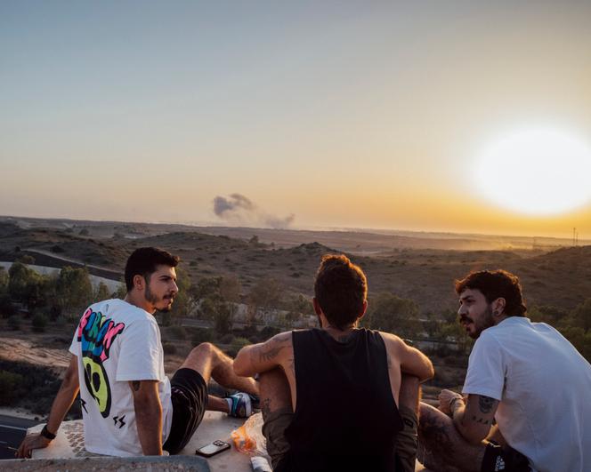Afik, Liram et Emmanuel, 27 ans tous les trois, viennent régulièrement au promontoire de Sderot (Israël) pour observer la guerre à Gaza, le 17 juillet 2025.