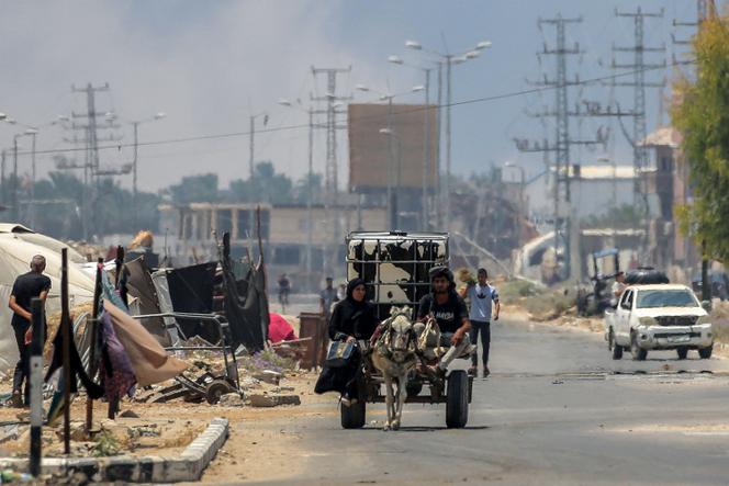 Un homme et une femme montent dans une charrette tirée par un âne et transportant une citerne d’eau, à Deir Al-Balah, dans le centre de la bande de Gaza, le 21 juillet 2025
