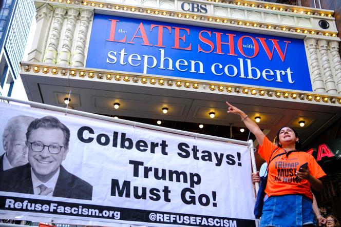 Des personnes participent à une manifestation intitulée « Colbert reste ! Trump doit partir », devant le théâtre Ed Sullivan à New York le 21 juillet 2025.  