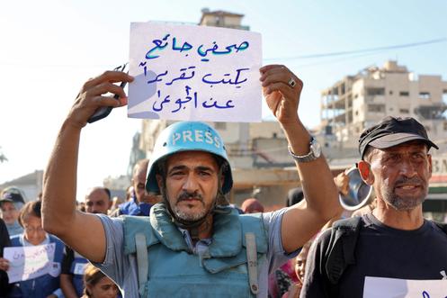 Un homme brandit une pancarte « un journaliste affamé écrit un reportage sur la famine », lors d’un rassemblement des journalistes de Gaza, à Gaza, le 19 juillet 2025.