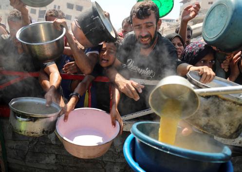 Des Palestiniens attendent de recevoir de la nourriture, alors que toute l’enclave est menacée de famine, dans la ville de Gaza, le 23 juillet 2025.
