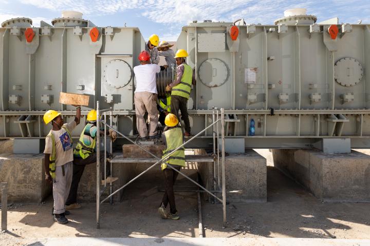 Des ouvriers de Manono Lithium travaillent sur le chantier d’un transformateur électrique qui viendra alimenter l’usine de traitement du lithium en cours de construction à Manono, le 22 mai 2025.