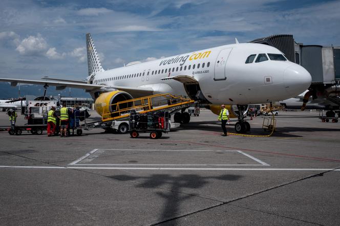 Des bagagistes chargent la soute d’un avion Airbus A320 de la compagnie aérienne low cost Vueling, à l’aéroport de Genève, le 28 juillet 2022.