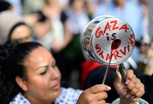 Une femme frappe une casserole portant l’inscription « Gaza meurt de faim », lors d’un rassemblement devant l’ambassade d’Egypte à Berlin, le 25 juillet 2025.
