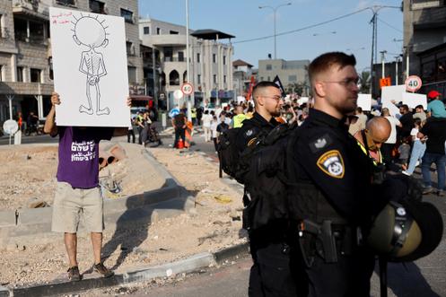 Un homme brandit une pancarte symbolisant un enfant palestinien affamé, lors d’un rassemblement à Sakhnin, en Israël, le 25 juillet 2025.