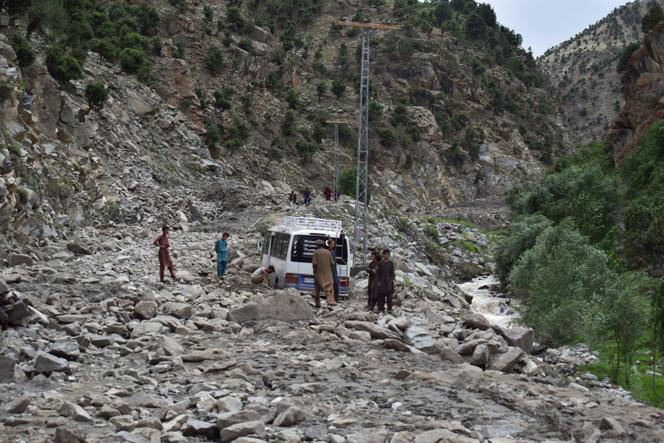 Des hommes dégagent une camionnette ensevelie sous des rochers après une crue, dans la région de Chilas, dans le nord du Pakistan le 23 juillet 2025. 