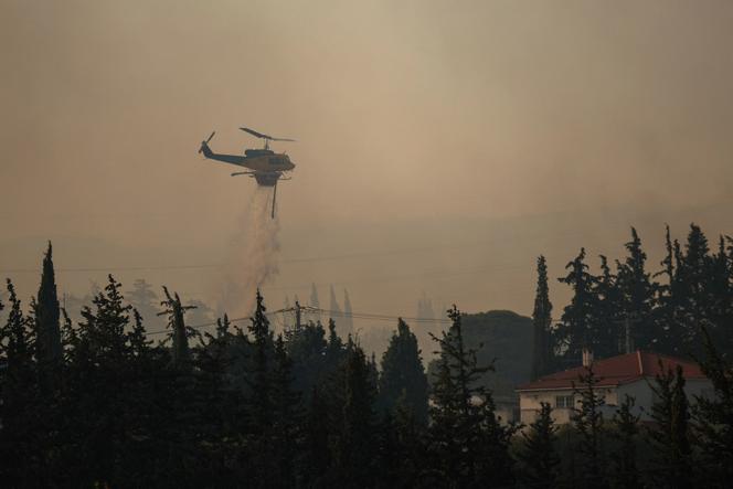 Un hélicoptère de lutte contre les incendies largue de l’eau lors d’un feu de forêt dans le village de Drosopigi, près d’Athènes, le 26 juillet 2025.