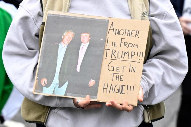 Une photo de Donald Trump posant avec Jeffrey Epstein est brandie par un manifestant anti-Trump à Balmedie (Ecosse), le 28 juillet 2025, jour de l’arrivée de Trump dans le pays.