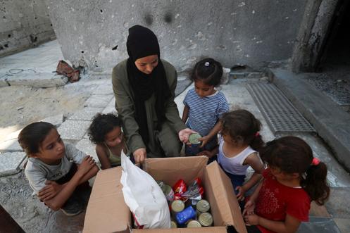 Amal Abu Assi, une mère palestinienne de trois enfants, ouvre le contenu d’un colis alimentaire parachuté qu’elle a reçu, à Gaza, le 28 juillet 2025.