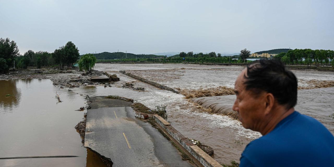 JADE GAO / AFP TOPSHOT - A damaged road is seen at a flooded area after heavy rains at Taishitun village in Miyun district, on the outskirts of Beijing on July 28, 2025. Torrential rain soaking northern China triggered a deadly landslide, burst riverbanks and washed away cars on July 28, with thousands of people forced to evacuate the days-long deluge. (Photo by Jade GAO / AFP)