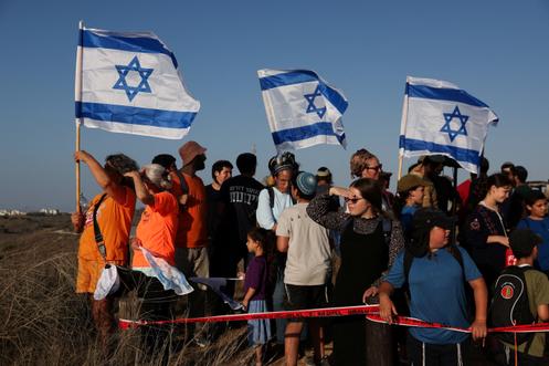 Des militants brandissent des drapeaux israéliens pour promouvoir la réinstallation de l’Etat hébreu à Gaza, lors d’un rassemblement organisé par des groupes de colons, du côté israélien de la frontière entre le pays et Gaza, le 30 juillet 2025.