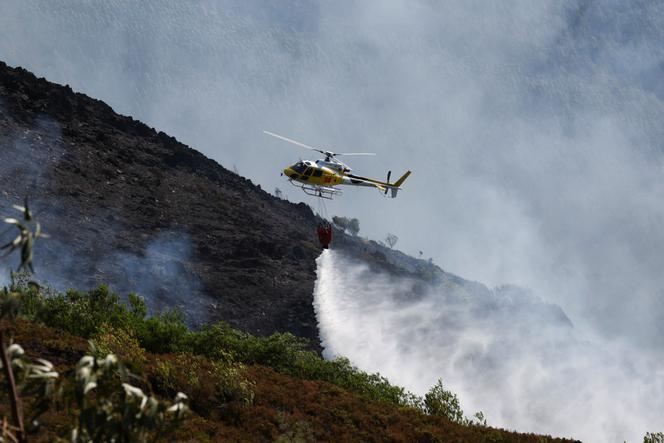 Un hélicoptère déverse de l’eau alors que les efforts pour lutter contre un incendie de forêt se poursuivent dans la région d’Arouca, au Portugal, le 30 juillet 2025. 