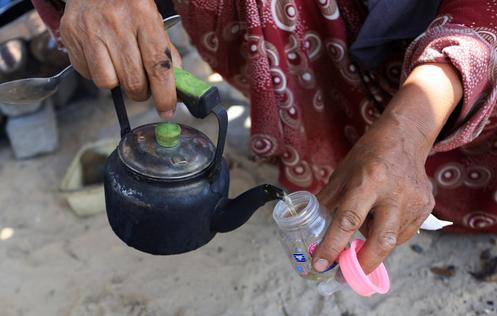 Une femme prépare un biberon d’eau aux herbes pour nourrir sa petite-fille de 3 mois, dans la ville de Gaza, le 29 juillet 2025.