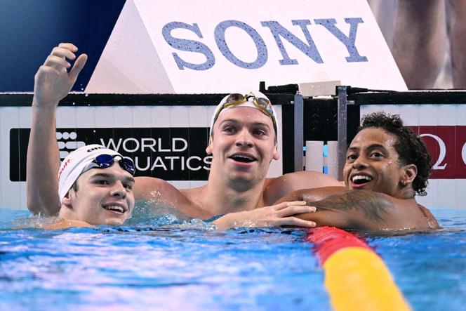 Le Français Léon Marchand (centre) après son sacre mondial sur 200 m quatre nages, entouré par l’Américain Shaine Casas (droite) et le Hongrois Hubert Kos, à Singapour, le 31 juillet 2025.