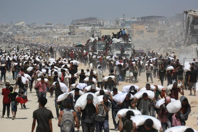 Récupération de sacs de farine par des Palestiniens, près de Jabaliya, dans le nord de la bande de Gaza, le 27 juillet 2025.