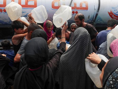 Des personnes déplacées dans un camp se rassemblent pour remplir des conteneurs d’eau, dans la ville de Gaza, le 1ᵉʳ août 2025.