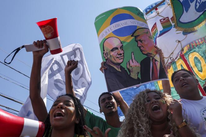 Un manifestant brandit une pancarte avec les portraits du juge de la Cour suprême brésilienne Alexandre de Moraes (à gauche) et  du président américain, Donald Trump, lors d’une manifestation contre les droits de douane imposés par Donald Trump aux produits brésiliens, devant le consulat américain à Sao Paulo, au Brésil, le 1ᵉʳ août 2025.
