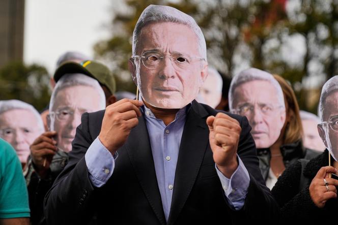 Les partisans de l’ancien président colombien Alvaro Uribe brandissent des masques à son effigie devant le tribunal où le verdict de son procès pour subornation de témoin est attendu, à Bogota, le 28 juillet 2025.