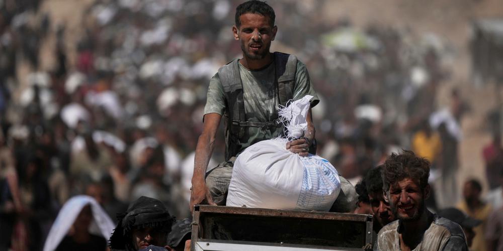 Des Palestiniens transportent des sacs de farine provenant d’un convoi d’aide humanitaire en route vers la ville de Gaza, dans la banlieue de Beit Lahya, au nord de la bande de Gaza, le 1ᵉʳ août 2025. - JEHAD ALSHRAFI / AP