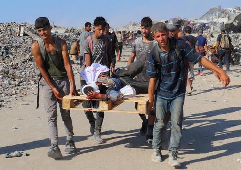 Des Palestiniens évacuent un homme blessé par des tirs israéliens, en le transportant à l’aide d’une palette utilisée pour les largages d’aide humanitaire, dans le nord de la bande de Gaza, le 3 août 2025.