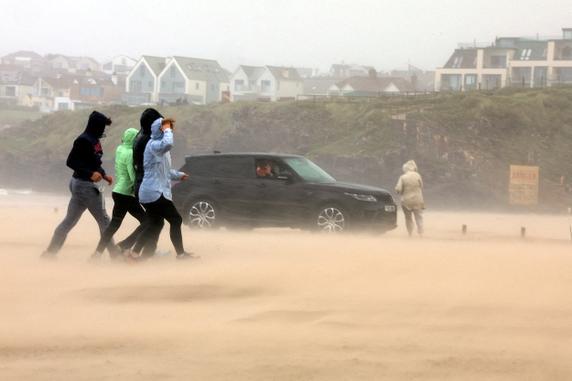 People run for cover during Storm Floris on the north coast of Northern Ireland, Portstewart, on August 4, 2025. 