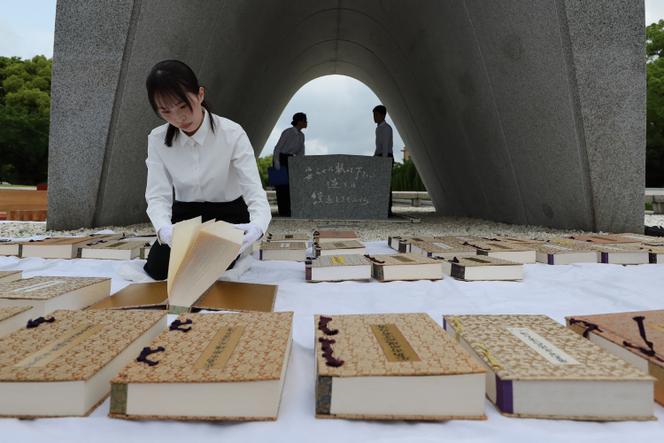 A city official in Hiroshima leafs through the list of atomic bomb victims, kept in the stone chamber of the cenotaph, at the Hiroshima Peace Memorial Park on May 22, 2025.