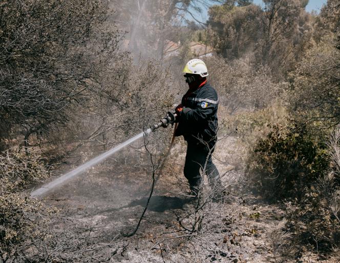 Un pompier rafraîchit un point chaud pour éviter une reprise de feu, dans les environs de Bages (Aude), le 9 juillet 2025