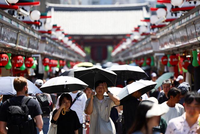 Des piétons sous des parasols dans le quartier d’Asakusa, un quartier touristique de Tokyo, au Japon, mardi 5 août 2025. 