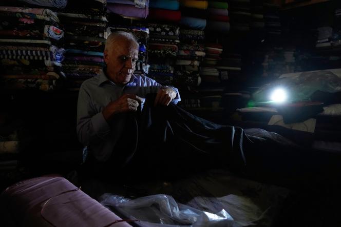Un vendeur de textile travaille dans son magasin pendant une panne d’électricité à Téhéran, le 5 août 2025.