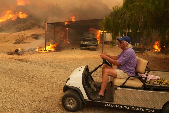 Un habitant évacue sa propriété atteinte par l’incendie, à Hasley Canyon (Californie), le 7 août 2025.