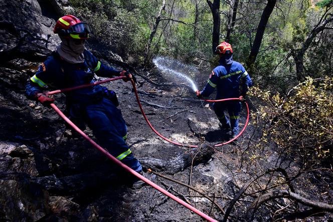 Dois bombeiros da Unidade de Operação Especial de Incêndios Wildfire, operam após um incêndio na vila de Charvalo, a sudeste de Atenas, Grécia, sábado, 9 de agosto de 2025. 
