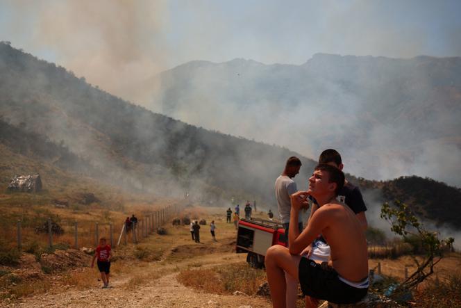 Des habitants observent les feux de forêt près de Tepelena, en Albanie, le 11 août 2025.
