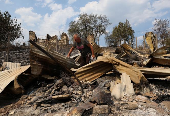 Clirim Coniku, 65 ans, marche à travers les décombres d’un bâtiment sur la propriété de sa famille, gravement endommagé par un incendie, à Skenderbegas, en Albanie, alors que des feux de forêt ravagent la région, le 13 août 2025.