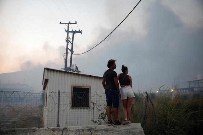 Des personnes observent un incendie de forêt à Sichaina, près de Patras, en Grèce, le 13 août 2025. 