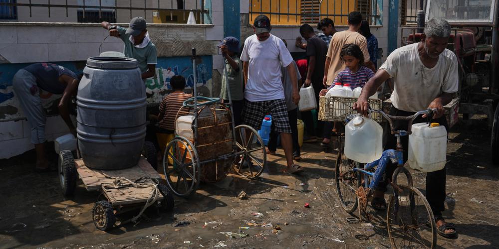 Des Palestiniens collectent de l’eau potable dans une usine de dessalement à Deir Al-Balah, dans le centre de la bande de Gaza, le 13 août 2025. - ABDEL KAREEM HANA / AP