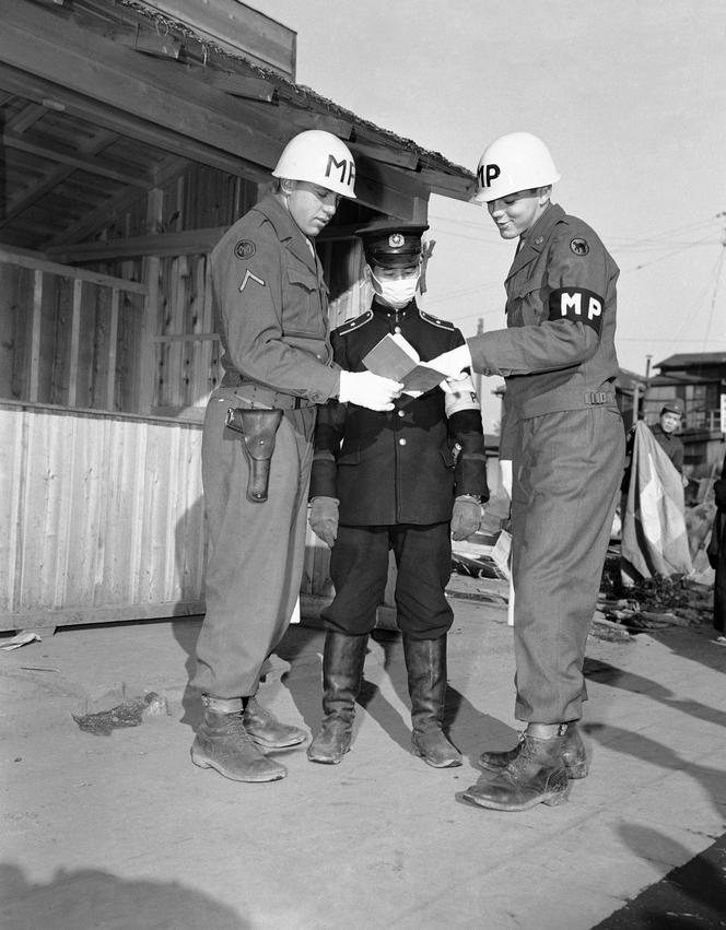 Les soldats Edward Linton et Eugene Weimer, originaires de l’Etat de New York, tous deux policiers militaires américains, accompagnent un policier japonais lors d’une patrouille dans les rues de Tokyo, le 26 janvier 1946.